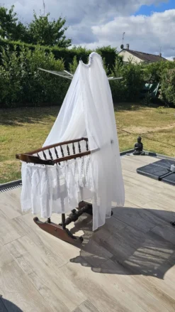 Bercelonnette ancienne à bascule en bois tourné et voilage plumetis