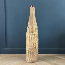 Bouteille en verre ambré dans son panier à poignée en osier