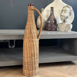 Bouteille en verre ambré dans son panier à poignée en osier
