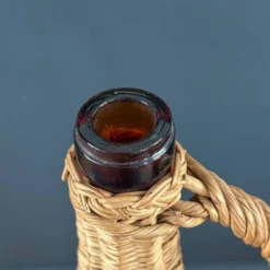 Bouteille en verre ambré dans son panier à poignée en osier