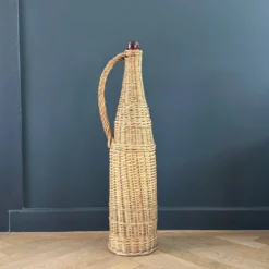 Bouteille en verre ambré dans son panier à poignée en osier