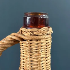 Bouteille en verre ambré dans son panier à poignée en osier