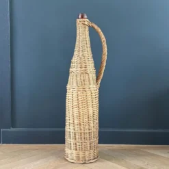 Bouteille en verre ambré dans son panier à poignée en osier