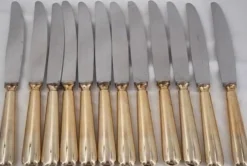 12 couteaux de table modèle Baguette, manches dorés, excellent état.