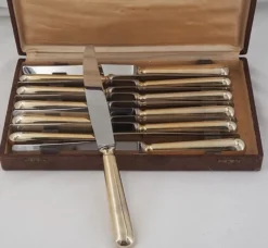 12 couteaux de table modèle Baguette, manches dorés, excellent état.