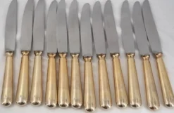 12 couteaux de table modèle Baguette, manches dorés, excellent état.