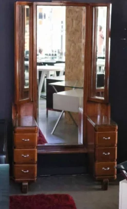 Hairdresser with a large shaped mirror and two pivoting side mirrors.