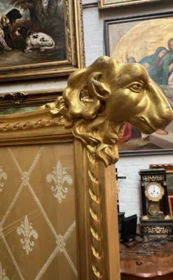 Paravent en bois doré décoré dans le style Louis XVI, orné de têtes de bélier.