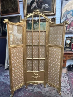 Paravent en bois doré décoré dans le style Louis XVI, orné de têtes de bélier.