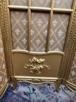 Paravent en bois doré décoré dans le style Louis XVI, orné de têtes de bélier.
