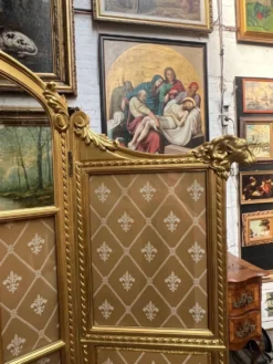 Paravent en bois doré décoré dans le style Louis XVI, orné de têtes de bélier.