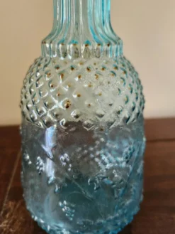 Petite carafe vintage en verre bleu turquoise moulé à décor floral