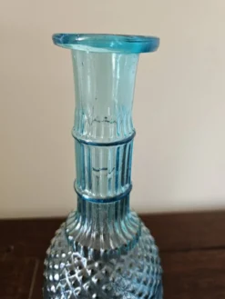 Petite carafe vintage en verre bleu turquoise moulé à décor floral