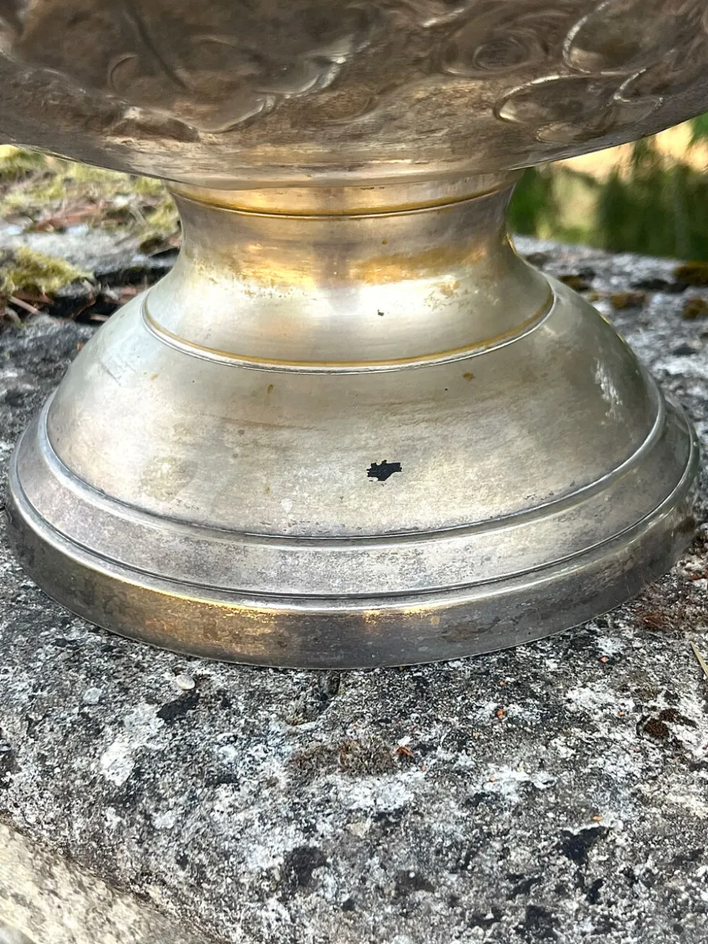 Seau à champagne en métal argenté sur piédestal avec des raisins.