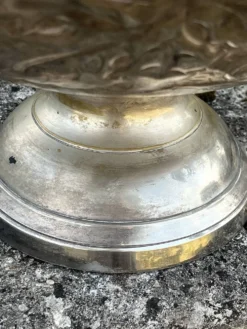 Seau à champagne en métal argenté sur piédestal avec des raisins.