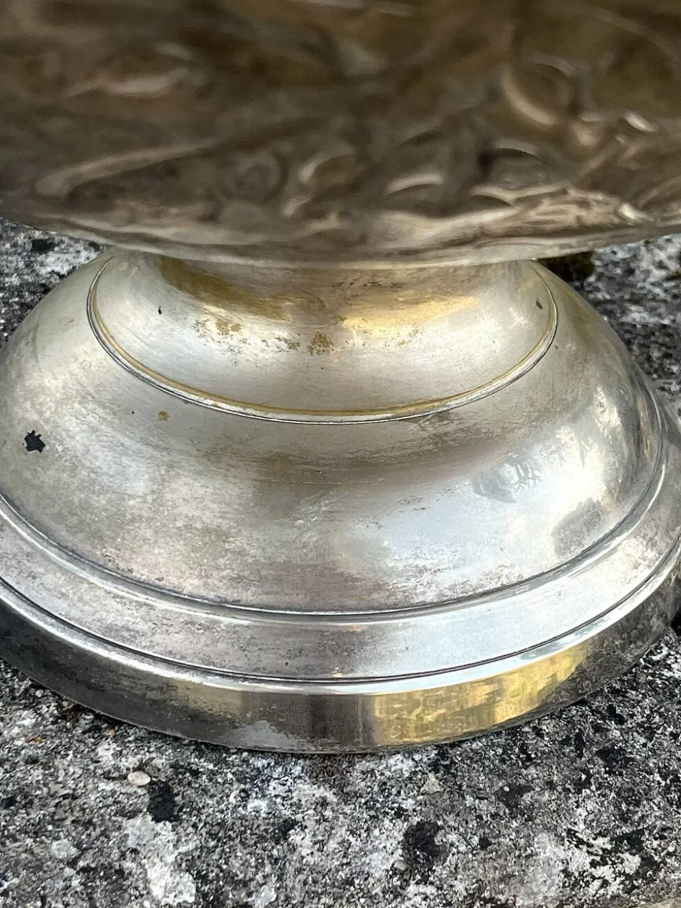 Seau à champagne en métal argenté sur piédestal avec des raisins.