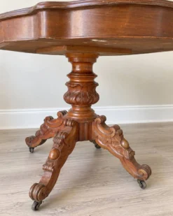 Table ancienne en bois sculpté – plateau chantourné et roulettes