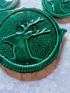 Un dessous de plat et deux de bouteilles en majolique verte Vallauris