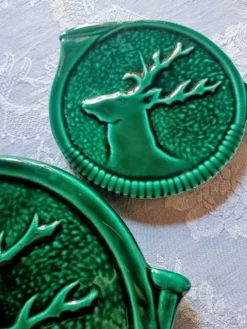 Un dessous de plat et deux de bouteilles en majolique verte Vallauris