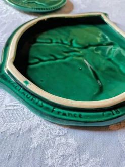 Un dessous de plat et deux de bouteilles en majolique verte Vallauris