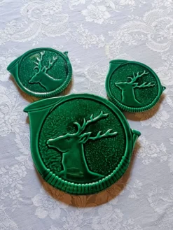 Un dessous de plat et deux de bouteilles en majolique verte Vallauris