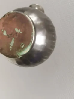 Une cruche en céramique avec un émail métallique et une poignée en raffia tressé.