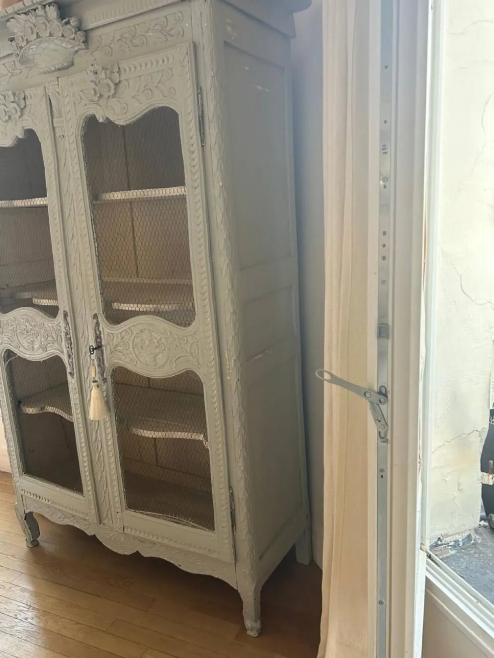 Vitrine ancienne française en bois sculpté avec portes en treillis métallique.